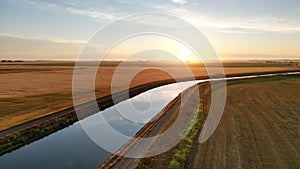 Aerial landscape of a river through a cultivated field at a dreamy sunrise