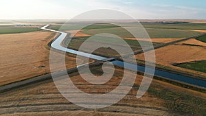 Aerial landscape of a river through a cultivated field at a dreamy sunrise