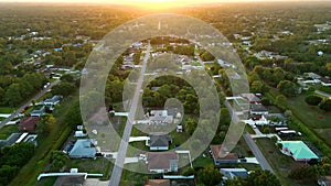 Aerial landscape view of suburban private houses between green palm trees in Florida quiet rural area at sunset