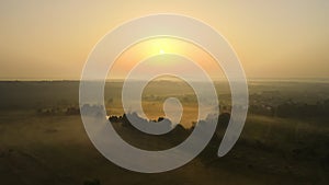 Aerial landscape view of sunny morning over foggy green fields