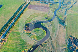 Aerial landscape of winding meanders small river, stream in green field, top evening sunset view meadow