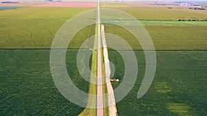 Aerial long straight road cutting across fields of farmland