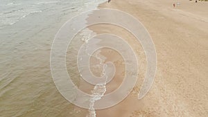 Aerial: low flight over baltic sea beach green ocean and waves going slowly