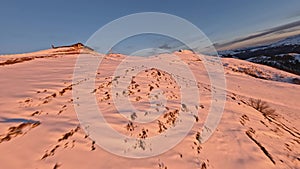 Aerial low speed view snow mountain peak ridge slope road at beautiful sunset