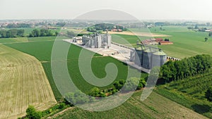 Aerial: modern industrial plant for agriculture produce processing and storage, cereal corn grain wheat crop fields.