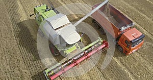 Aerial motion around thresher filling truck with wheat