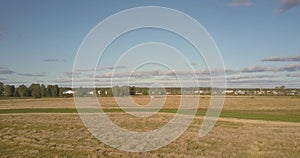 Aerial motion over ripe wheat field to farm against blue sky