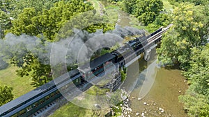 Aerial Narrow Gauge Steam Passenger Train, Traveling Crossing a Bridge Over a Stream, Blowing Smoke