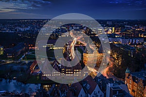 Aerial night view of the illuminated city of Luebeck, Germany in winter with Holstentor and historic Salzspeicher houses, long