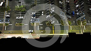 Aerial night view of many cars parked on parking lot with lines and markings for parking places and directions. Place