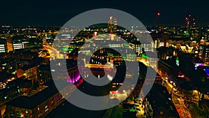 Aerial night view of a vibrant cityscape with illuminated buildings and streets in Leeds, UK