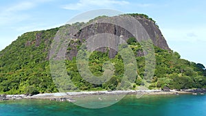 Aerial of Nosy Ankarea Madagascar over the forest past massive granite hill approaching the beach, near Nosy Be