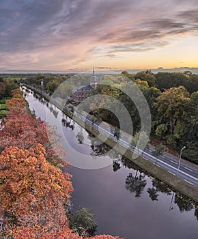 Aerial of the Nyenrode castle next to the vecht river during an amazing autumn sunset with pink colours and orange trees