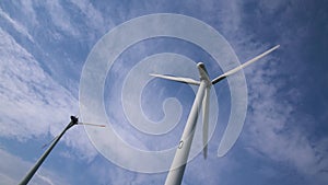 Aerial orbiting shot of a row of windmills with white clouds.