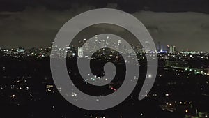 Aerial: over dark Hollywood Los Angeles at night with clouds over downtown and city lights