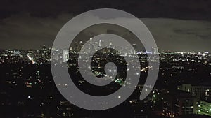 Aerial: over dark Hollywood Los Angeles at night with clouds over downtown and city lights