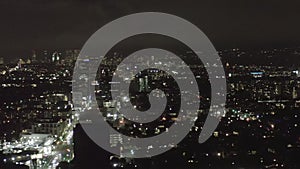 AERIAL: Over Dark Hollywood Los Angeles at Night view on Wilshire Blvd with Clouds over Downtown and City Lights