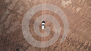 Aerial over off road 4x4 car driving along gravel trail path. Overhead on white offroad vehicle on desert Pamir Highway