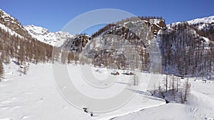 Aerial over winter wonderland, snowy mountain valley in sunny winter day.Winterland scene with lodges and people walking