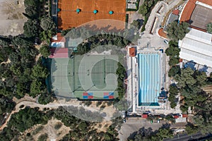 Aerial overhead drone shot of hard and clay tennis court besides swimming pool in Athens