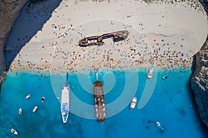 Aerial overhead drone shot of Zakynthos Navagio beach full of tourists and cruise ship in Ionian sea in Greece