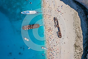 Aerial overhead drone shot of Zakynthos Navagio beach full of tourists and cruise ship in Ionian sea in Greece