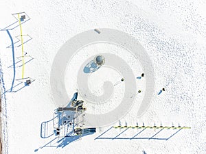 Aerial overhead drone view of school playground equipment covered in snow.