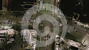 Aerial: overhead rising on intersection street with big construction site and holes in ground at night with glowing