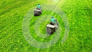 Aerial. Pair of lawn mowers on a grass. Professional gardening background with a two workers on lawnmowers