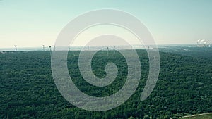 Aerial pan shot of distant smoking stacks of a traditional power plant and modern wind farm. Clean energy production