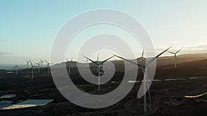 Aerial panning drone shot of wind turbines plant at sunset.