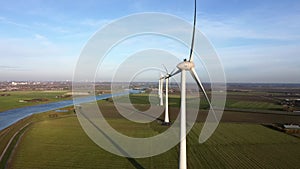 Aerial panning shot of rotating wind turbines in a Dutch landscape.