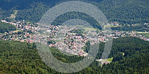 Aerial panorama of Busteni village in Prahova Valley, surrounded by forest, a popular outdoor destination in Romania