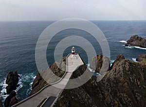 Aerial panorama of Cabo Ortegal lighthouse on steep rocky cliff atlantic ocean bay of biscay Carino Cape Galicia Spain