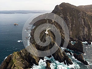 Aerial panorama of Cabo Ortegal lighthouse on steep rocky cliff atlantic ocean bay of biscay Carino Cape Galicia Spain photo