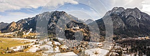 Aerial panorama drone shot of picturesque Neuschwanstein Castle on snowy hill in winter sunlight in Germany