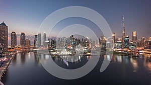 Aerial panorama of Dubai Business Bay and Downtown with the various skyscrapers and towers day to night timelapse