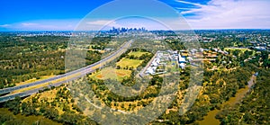 Aerial panorama of Eastern Freeway and Melbourne CBD skyscrapers on bright summer day.