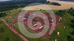 Aerial panorama of oil pumps at oilfield cluster. Summer morning, the working oil pumps and drilling rig among the