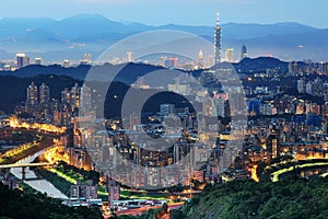 Aerial panorama of overpopulated suburban communities in Taipei at dusk, with Taipei 101 Tower among buildings in downtown