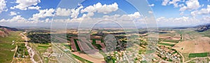 Aerial panorama of patchwork fields with shadows cast by clouds and a rural settlement