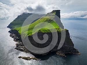 Aerial panorama of a small white lighthouse located on the edge of a huge cliff and the island of Kalsoy. Kalsoy is an isolated photo