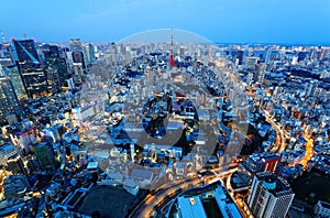 Aerial panorama of Tokyo Downtown at blue dusk, with view of illuminated Tokyo Tower among crowded buildings