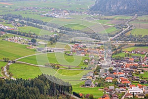 Aerial panorama of towns and highways in a valley surrounded by Alpine mountains