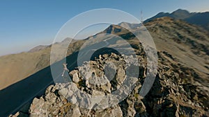 Aerial panorama view extreme man running on stone peak of high mountain sunset sunrise natural glare