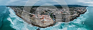 Aerial panoramic drone view of Azenhas do Mar, a small Portuguese village situated on edge of steep cliff in a stunning location