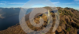 Aerial panoramic drone view of a lighthouse over Lake Como skyline with sunset light