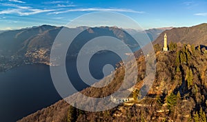 Aerial panoramic drone view of a lighthouse over Lake Como skyline with sunset light