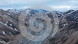 Aerial panoramic footage of wide valley with riverbed between mountain ridges with snowfields. Thorsmork valley, Iceland