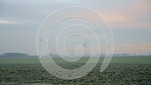Aerial panoramic landscape of green meadow and windmills on foggy day. Amazing view on wind turbines generating energy